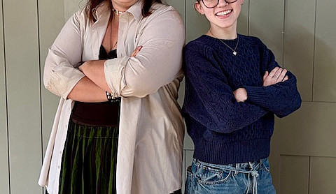 2 college students standing back to back with arms crossed