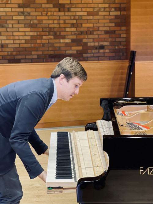 Luca slides the keyboard back into the body of the piano