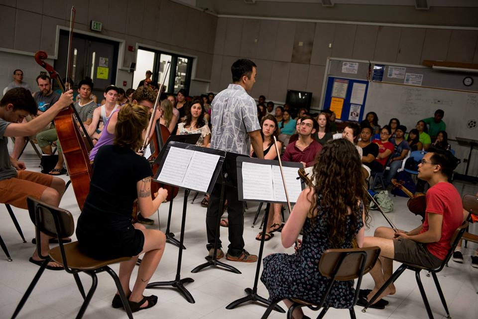 Lance Inouye prepares to conduct LC string quintet performance for local high school