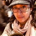 Dr. Leonard wearing a hat and scarf, holding a cup of coffee
