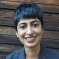 Sidra is smiling in front of a wooden background