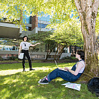 Students study outside under a tree.